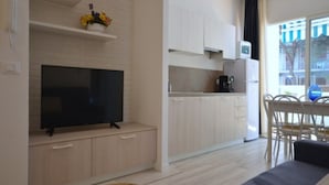A modern living room with a flat-screen TV, a sofa, and a small wooden stool.