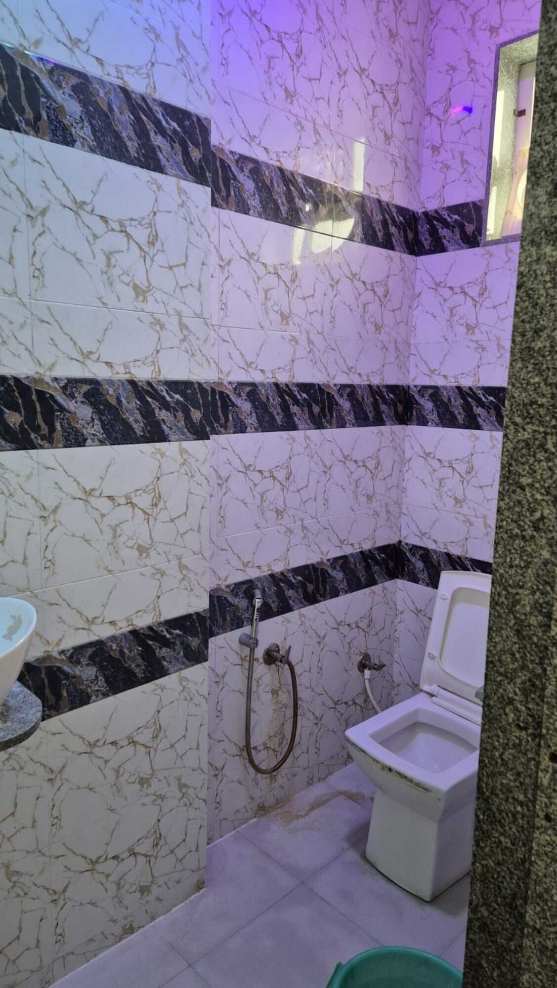 Une salle de bain avec des carreaux de marbre noir et blanc, des toilettes, un lavabo et une douche.