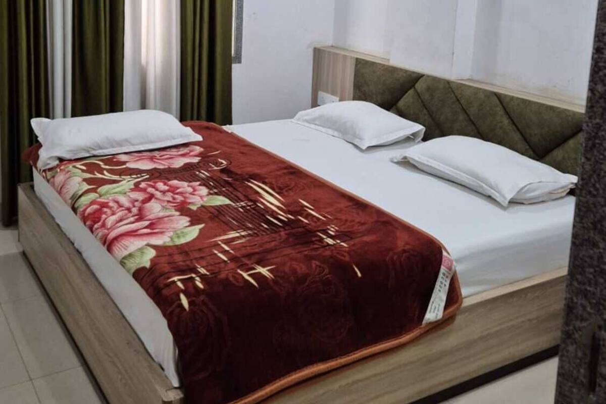 A bedroom with a bed, curtains, an air conditioning unit, and a ceiling fan.