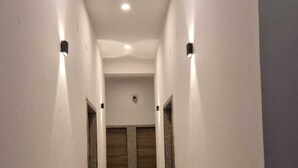 A narrow, well-lit hallway with a tiled floor and two doors at the end. - Shree Hanuman Hotel (Shri Madhopur)