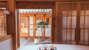 Ett traditionellt japanskt rum med tatamimattor på golvet, en shoji-skjutdörr och ett litet bonsaiträd.