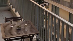 Een balkon met een tafel en stoelen, met uitzicht op een strand en de zee.