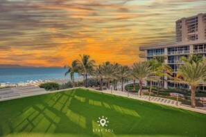 A resort with a pool, palm trees, and a view of the ocean at sunset. - Spectacular Apt - Sea View Luxury & Free Parking (Miami Beach)