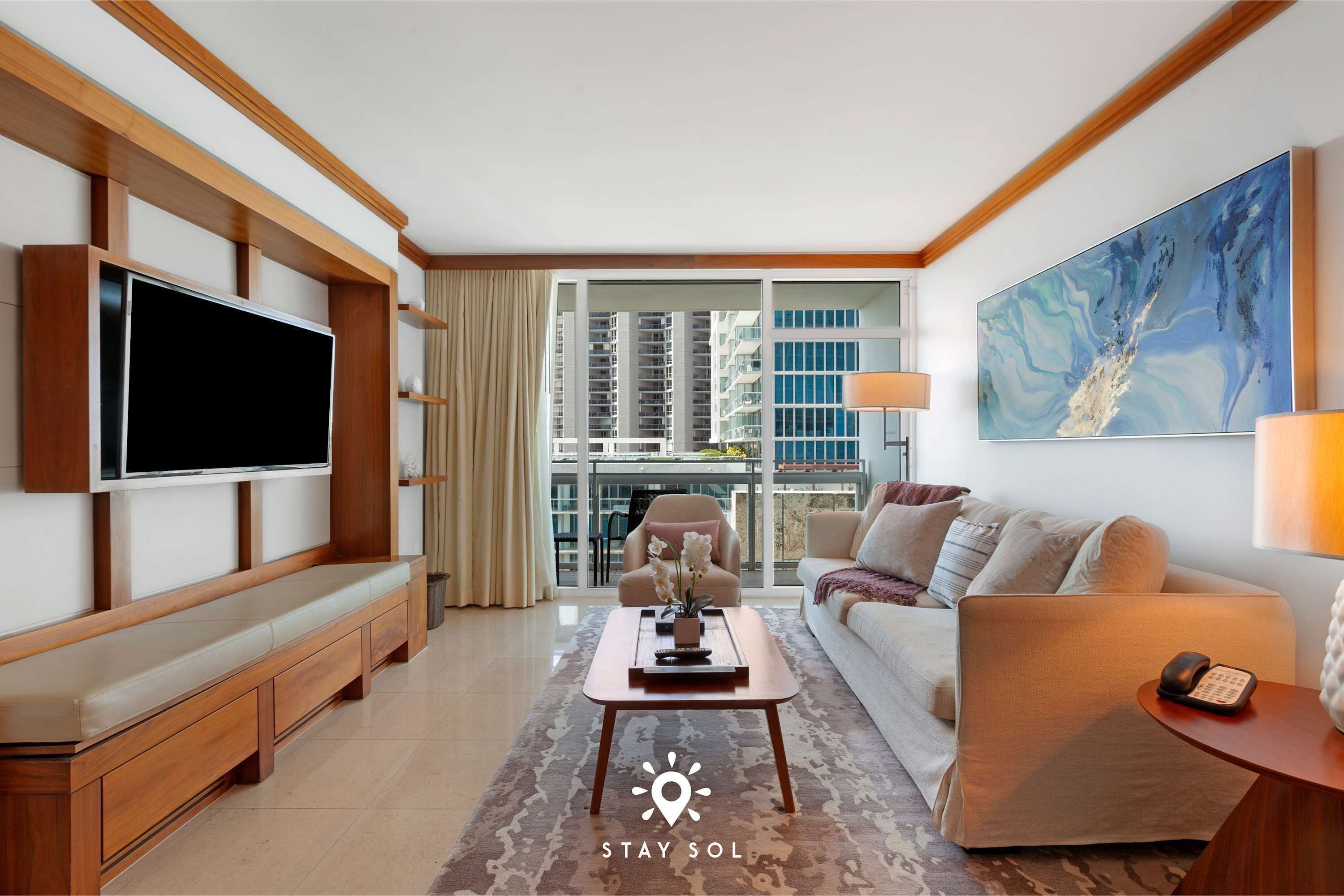 A modern living room with a flat-screen TV, a sofa, a coffee table, and a painting on the wall.