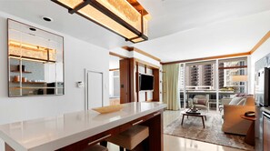 A modern kitchen with a large island, a dining area with a sofa, and a view of the city through large windows. - Amazing 1BR Apt - Beach view & Free Parking (Miami Beach)