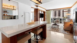 Una cocina moderna con una isla grande, un comedor con sofá y vistas de la ciudad a través de amplios ventanales.
