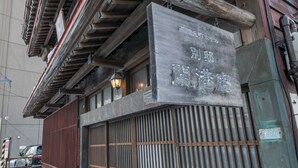 Un edificio tradicional japonés con fachada de madera y una reja metálica.