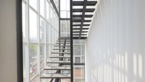 Ein modernes Interieur mit einer Treppe zu einem Balkon, großen Fenstern und Außenblick.