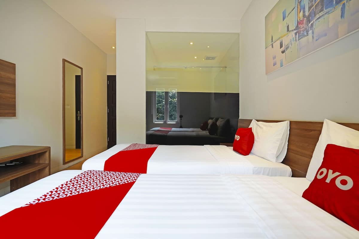 Une chambre d’hôtel avec deux lits, un bureau, un miroir et un tableau au mur.