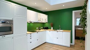 Een moderne keuken met witte kastjes, een ingebouwde oven en een groene accentmuur.