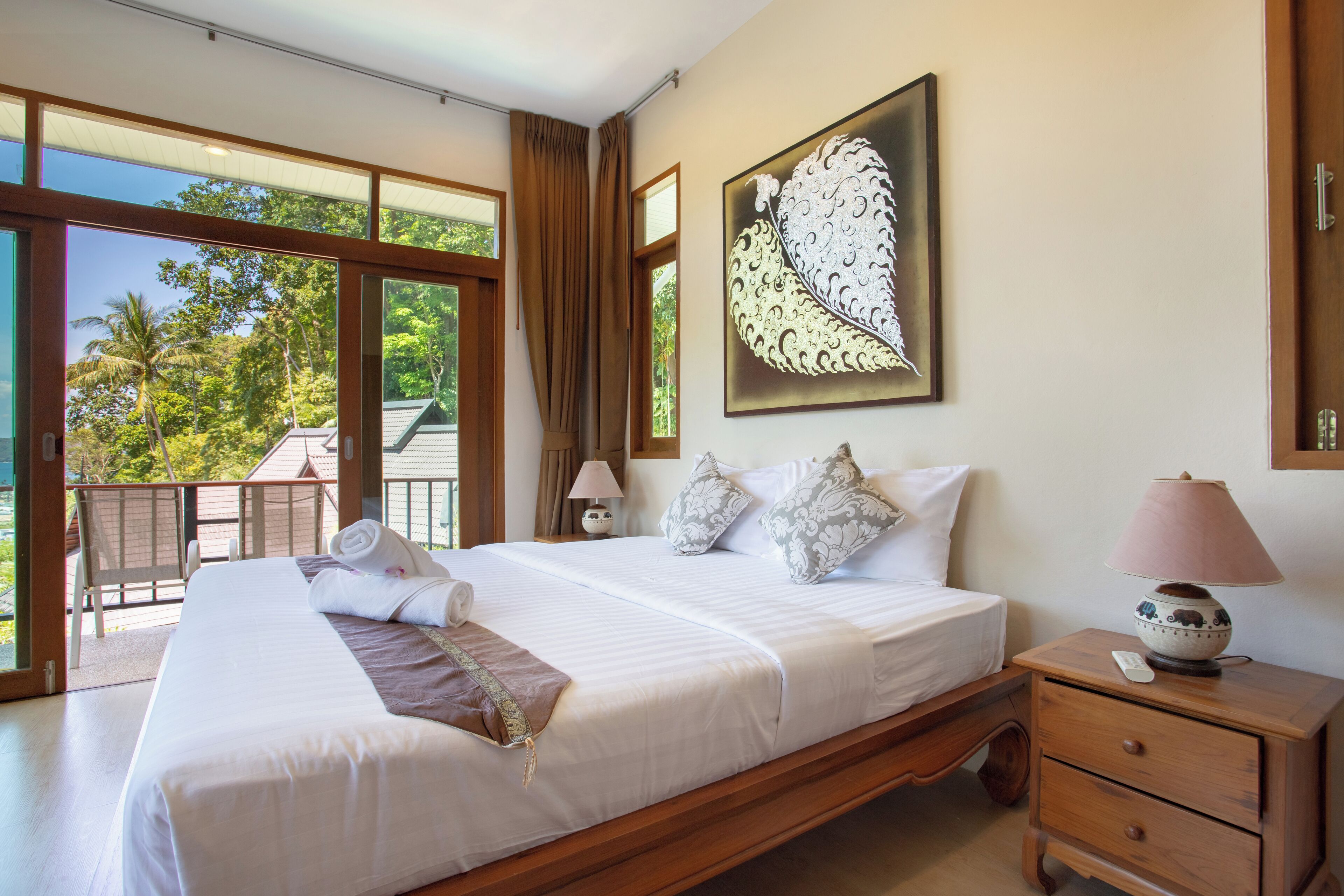 A spacious bedroom with a large bed, a nightstand, and a view of the outdoors.