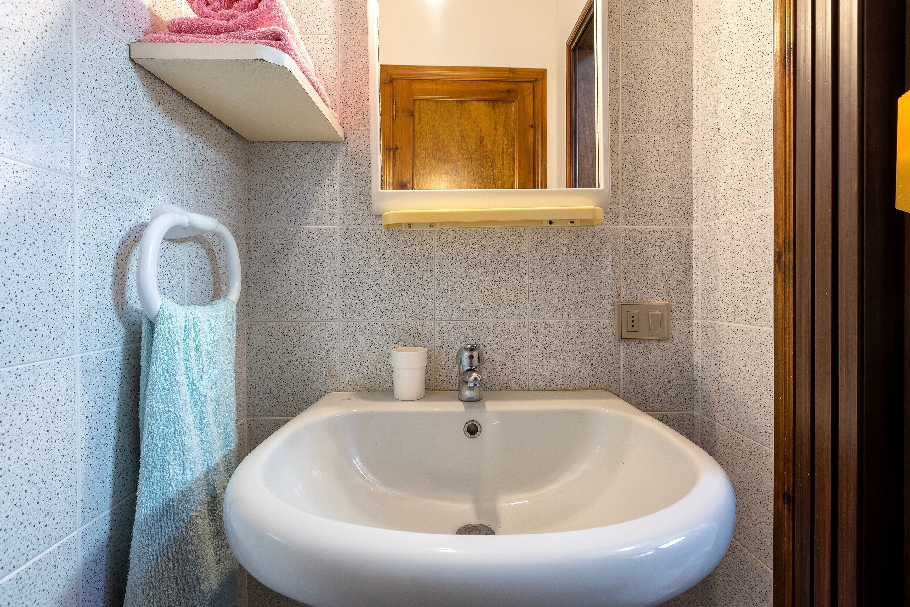 Ein Badezimmer mit Waschbecken, Handtuchhalter, Spiegel und Ablagefläche mit einem Handtuch.