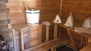 L’intérieur d’un chalet en bois, avec un sauna, un banc et des sacs étiquetés « Чарів » et « Парино ».