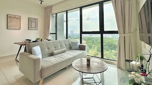 Ein modernes Wohnzimmer mit einer Couch, einem Couchtisch und einem großen Fenster mit Blick auf die Stadt.