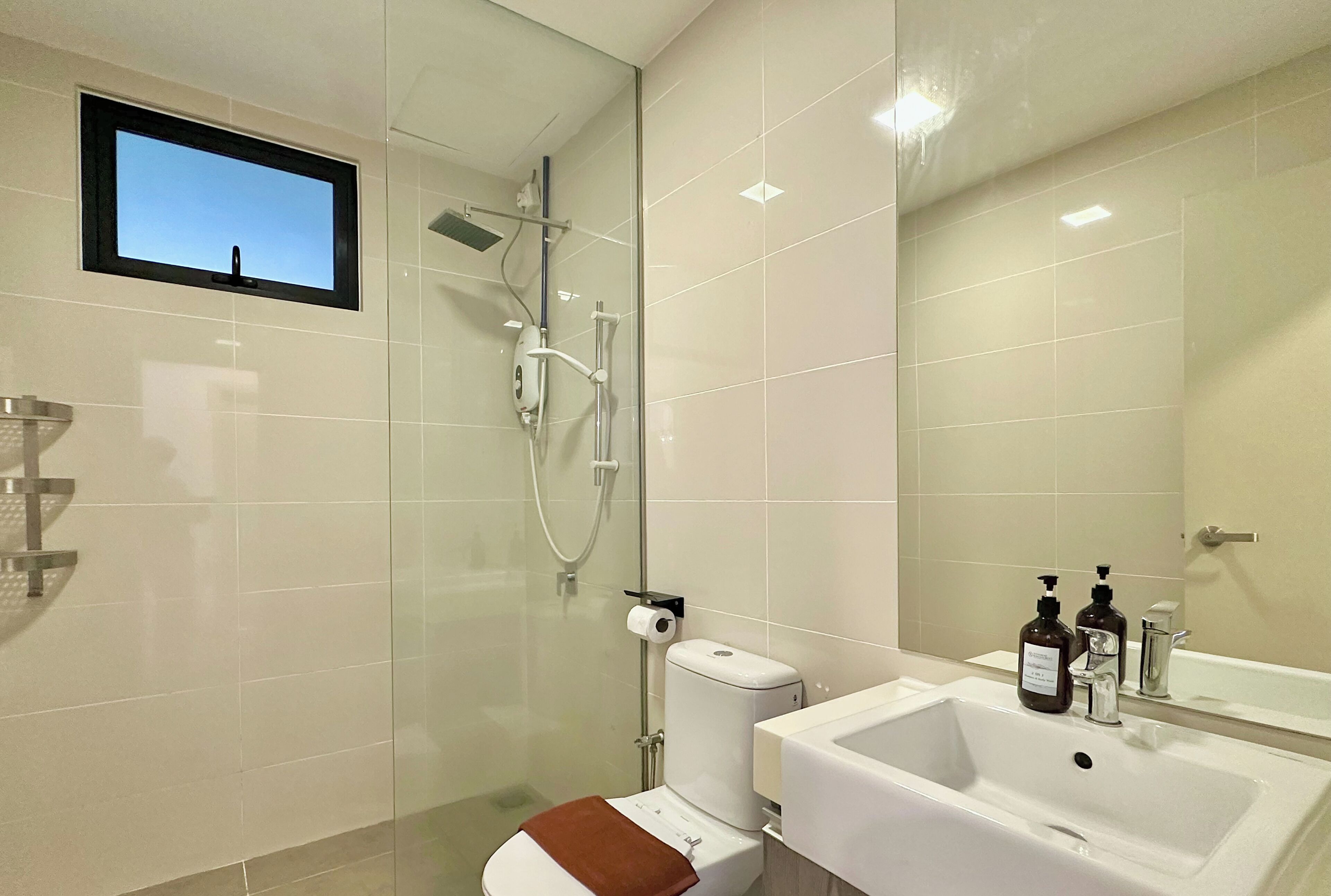 Un baño moderno con ducha acristalada, inodoro, lavabo y un espejo grande.