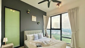Ein modernes Schlafzimmer mit einem großen Bett, einem Deckenventilator, Blick auf die Stadt und einer grünen Akzentwand.