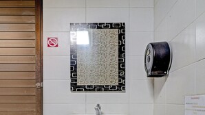 A restroom with a white sink, a toilet, and a paper towel dispenser. - OYO 94732 D River Cihampelas (Bandung)