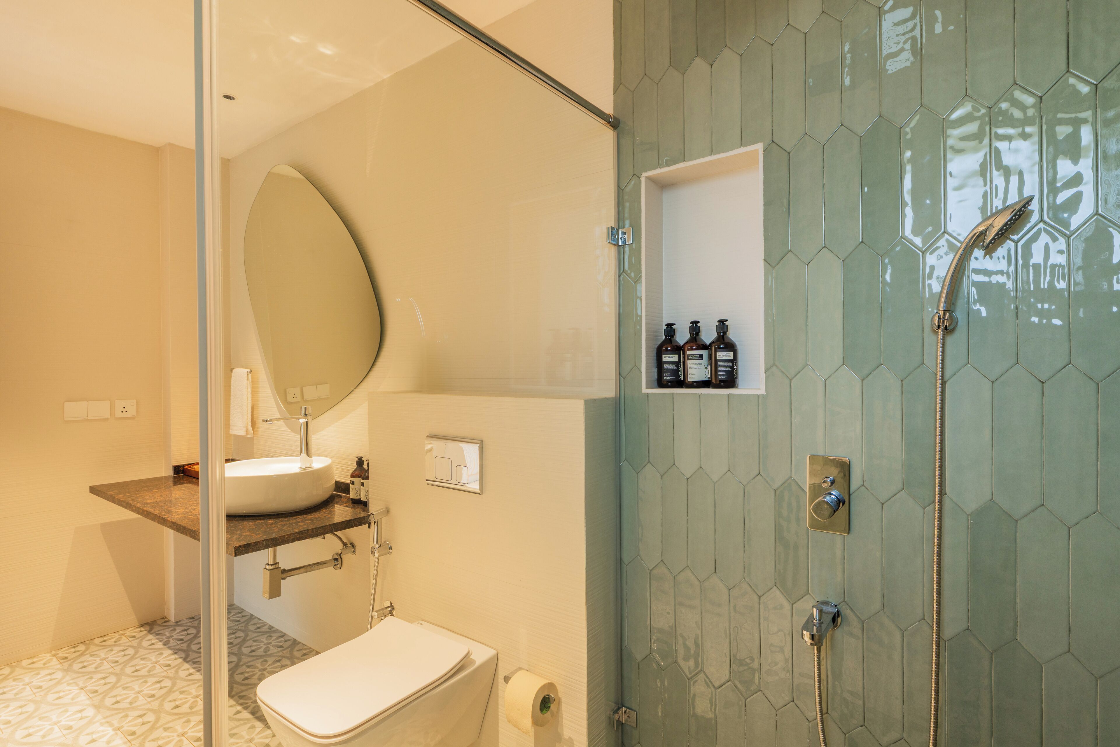 A modern bathroom with a glass-enclosed shower, a sink with a mirror above, and a toilet.