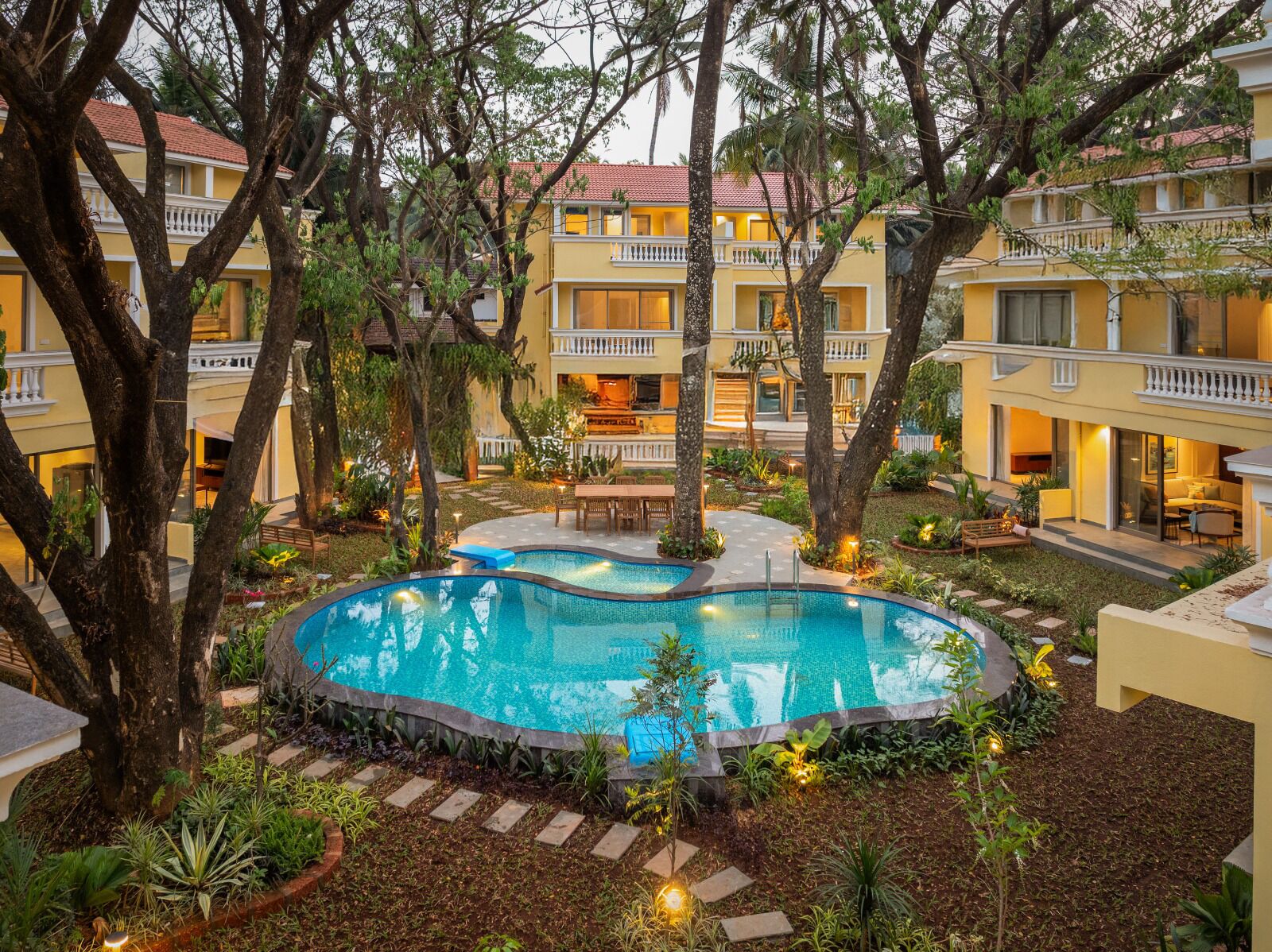 Un hotel con piscina rodeado de árboles y un jardín bien cuidado.