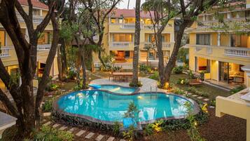 Un hotel con piscina rodeado de árboles y un jardín bien cuidado.