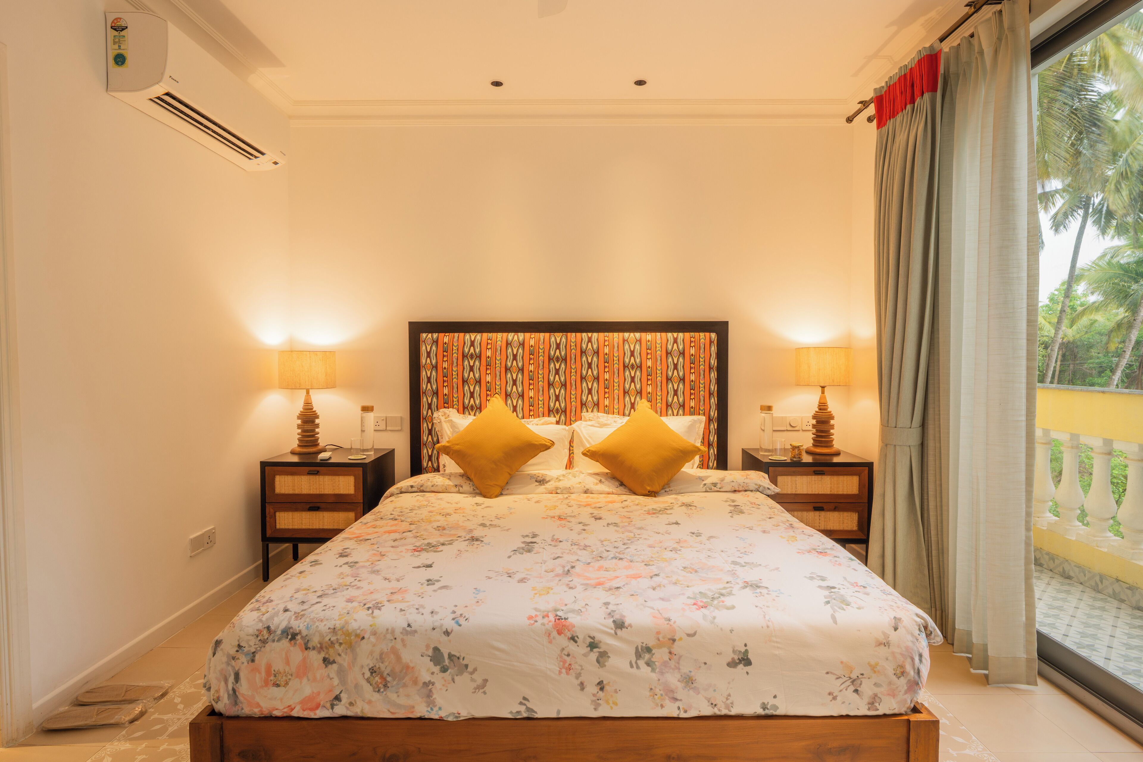 A bedroom with a bed, two bedside tables, a headboard, and a window with curtains.