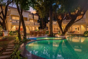 A resort with a swimming pool, outdoor seating, and multiple balconies. - ELIVAAS Kensho Hibiscus 3BHK Villa (Utorda)