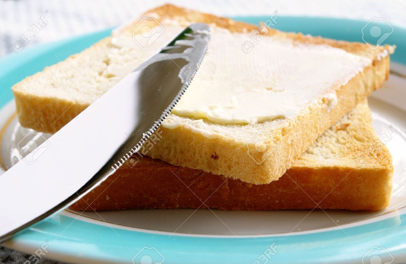 Una rebanada de pan blanco con mantequilla sobre un plato.