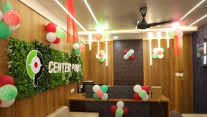 Un espace d’accueil avec un comptoir de réception en bois, des décorations murales vertes et des ballons colorés.