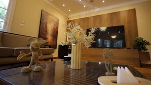 Un salon moderne avec un canapé, une table basse agrémentée d’objets décoratifs, un téléviseur à écran plat et un mur d’accent en bois.