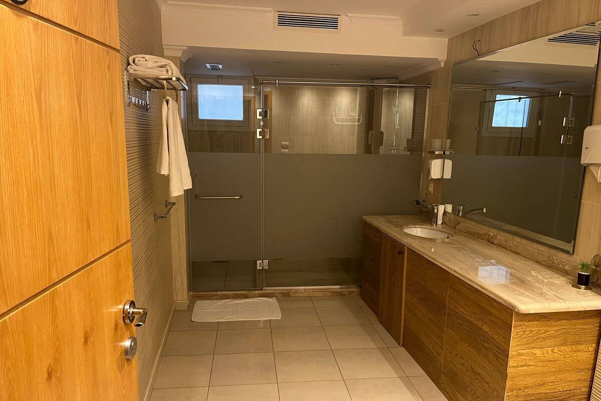 A modern bathroom with a wooden vanity, a glass shower enclosure, and a large mirror.