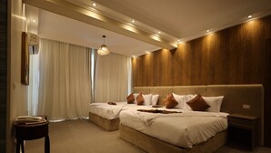 Une chambre d’hôtel avec deux lits, une tête de lit en bois, une table de chevet et une grande fenêtre avec des rideaux.