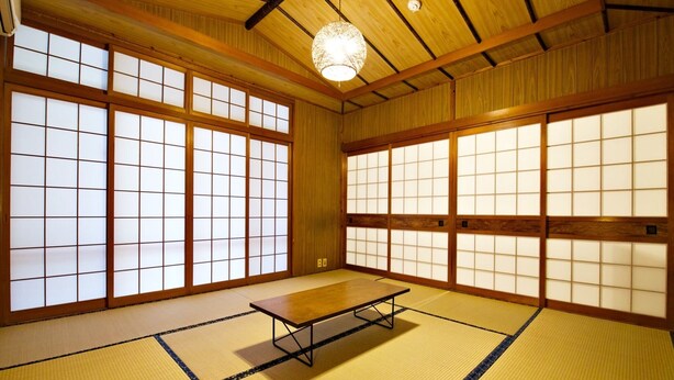 A traditional Japanese room with tatami flooring, sliding doors, and a low wooden table. - Onnason Yamada House (Onna)
