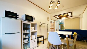 A compact kitchen with a refrigerator, microwave, and a small dining area with a table and chairs. - Onnason Yamada House (Onna)