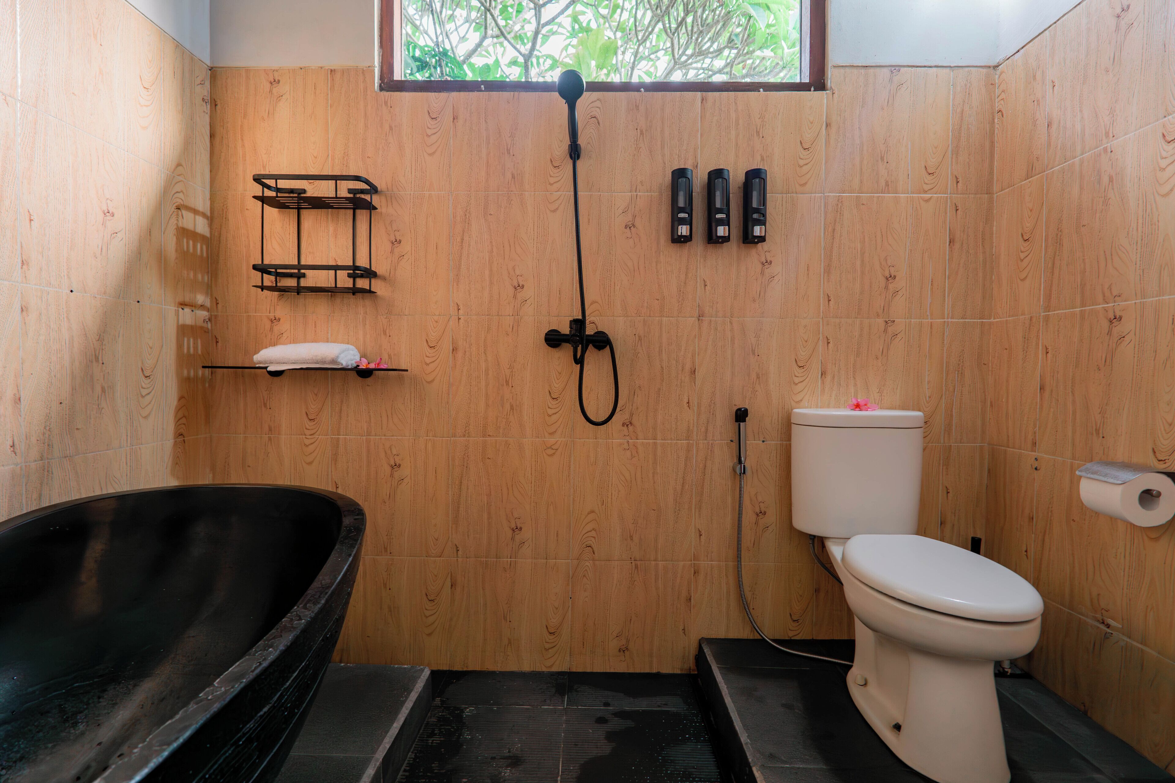A bathroom with a black bathtub, a toilet, and a shower head.