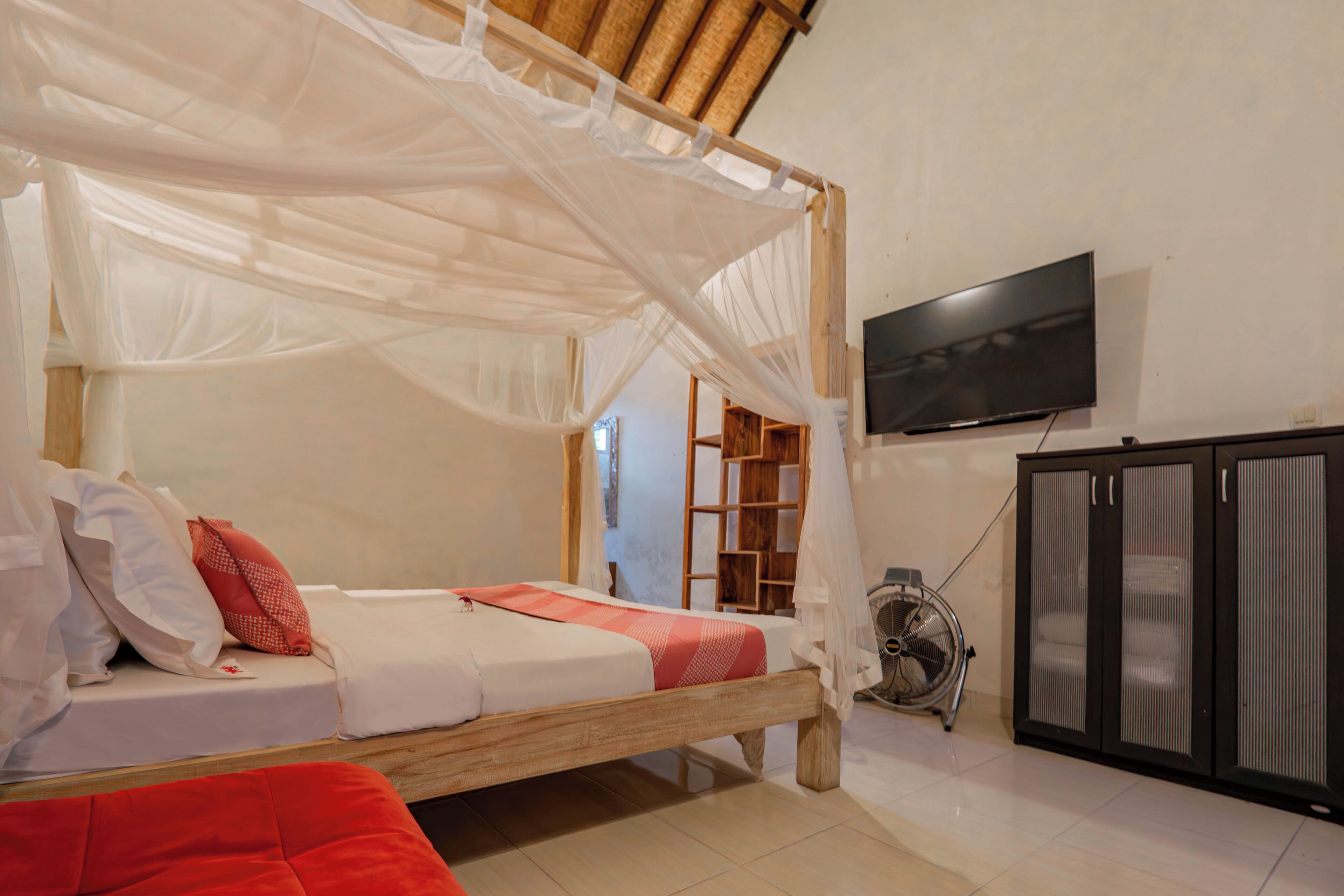Un dormitorio con cama de madera, ropa de cama blanca, un televisor en la pared y un armario.