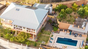 An aerial view of a property with a swimming pool, a covered patio, and a building with a sloped roof. - Spacious 2-bedroom apartment in Avirons - Terrace & Parking (Les Avirons)
