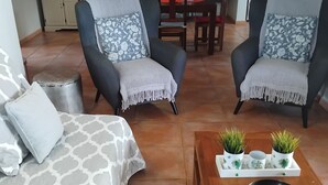 A living room with two armchairs, a sofa, a coffee table with plants, and a dining area in the background. - Spacious 2-bedroom apartment in Avirons - Terrace & Parking (Les Avirons)