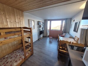 A cozy room with a bunk bed, a sofa, a dining table, and a TV.