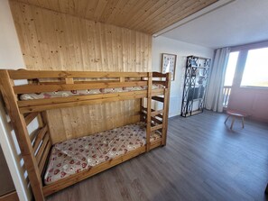 Una cama individual superpuesta con colchón estampado en una habitación con piso de madera y techo inclinado.