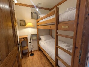 Ein Zimmer mit Etagenbett, Nachttisch, Lampe und Deckenventilator.