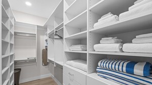 A walk-in closet with white shelving units, some with folded towels and one with a striped towel. - Chic Uptown Condo Tucson (Tucson)