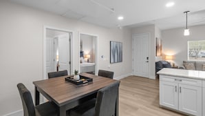 A modern kitchen with white cabinets, a wooden dining table, and a central island. - Chic Uptown Condo Tucson (Tucson)
