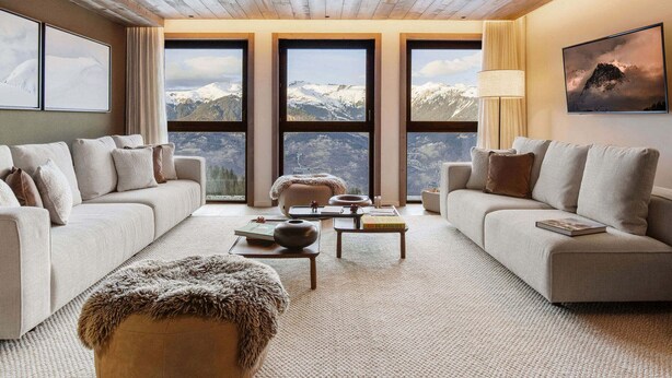 A spacious living room with two sofas, a coffee table, and a view of snow-capped mountains through large windows. - Luxury Apartment in Courchevel 1850 with Suites and Wellness Access (Courchevel 1850)