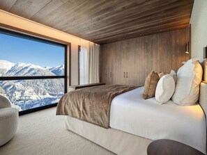 A bedroom with a large window, wooden ceiling, and a bed with pillows. - Luxury apartment in Courchevel 1850 center with spa access and shuttle service (Courchevel 1850)