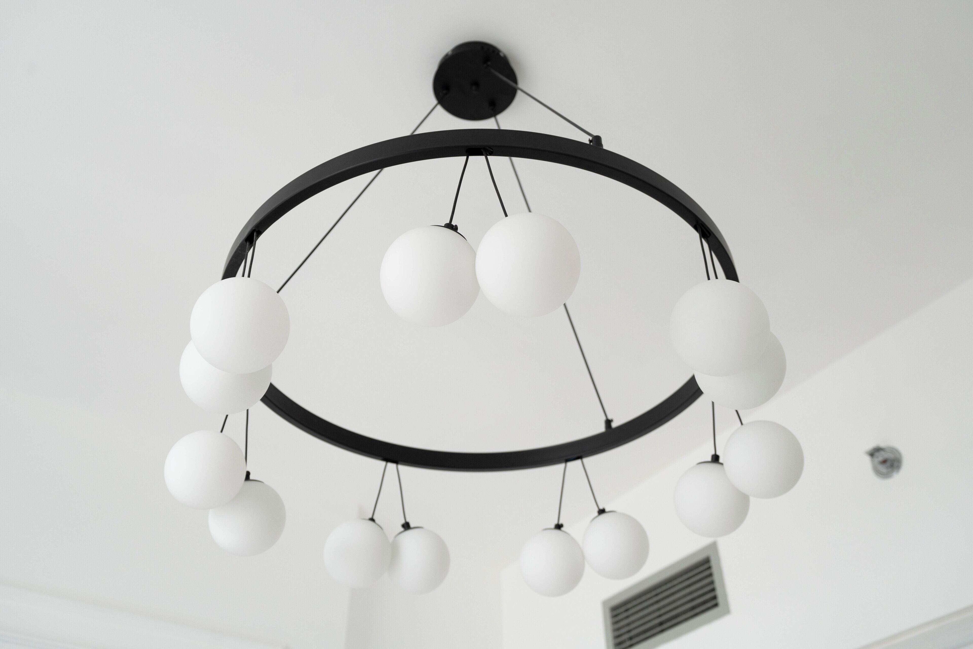 A modern chandelier with multiple spherical lights hanging from a circular frame.