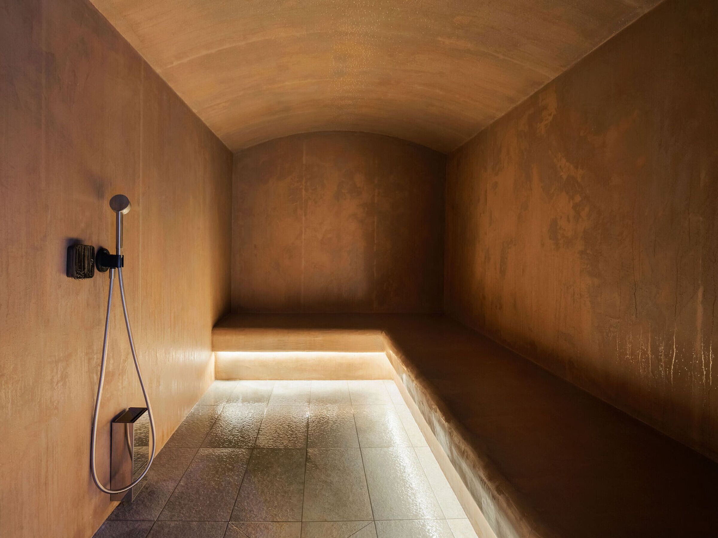 A minimalist bathroom with a shower, a towel rack, and a tiled floor.