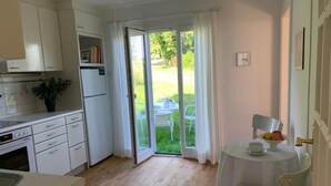 A compact kitchen with a dining area, a small table with chairs, and a sliding glass door leading to a patio.