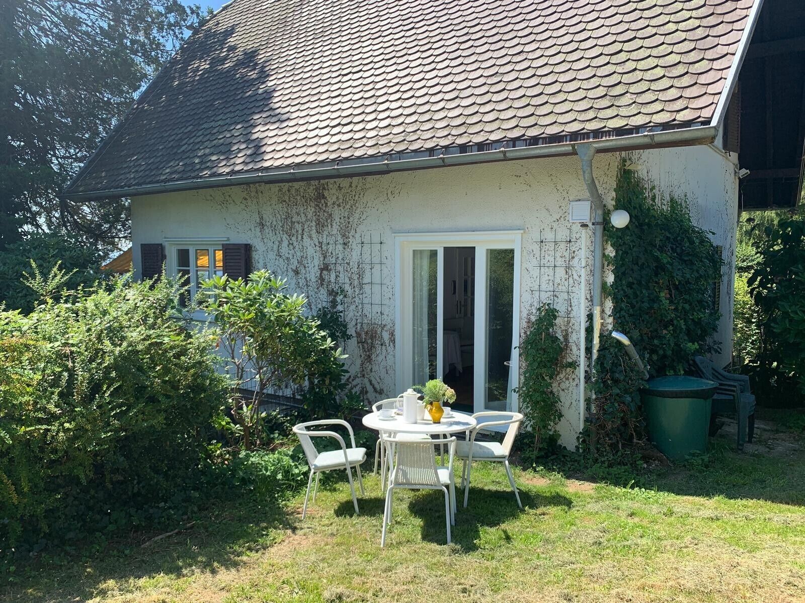 Una casa con tetto in tegole, una porta bianca e un piccolo patio con tavolo e sedie.