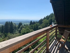 A wooden deck with a view of a forest and distant mountains.