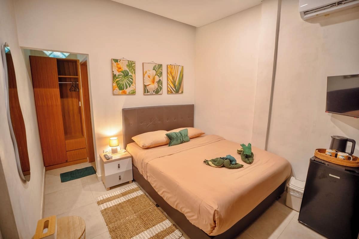 A bedroom with a bed, nightstand, and a small refrigerator.